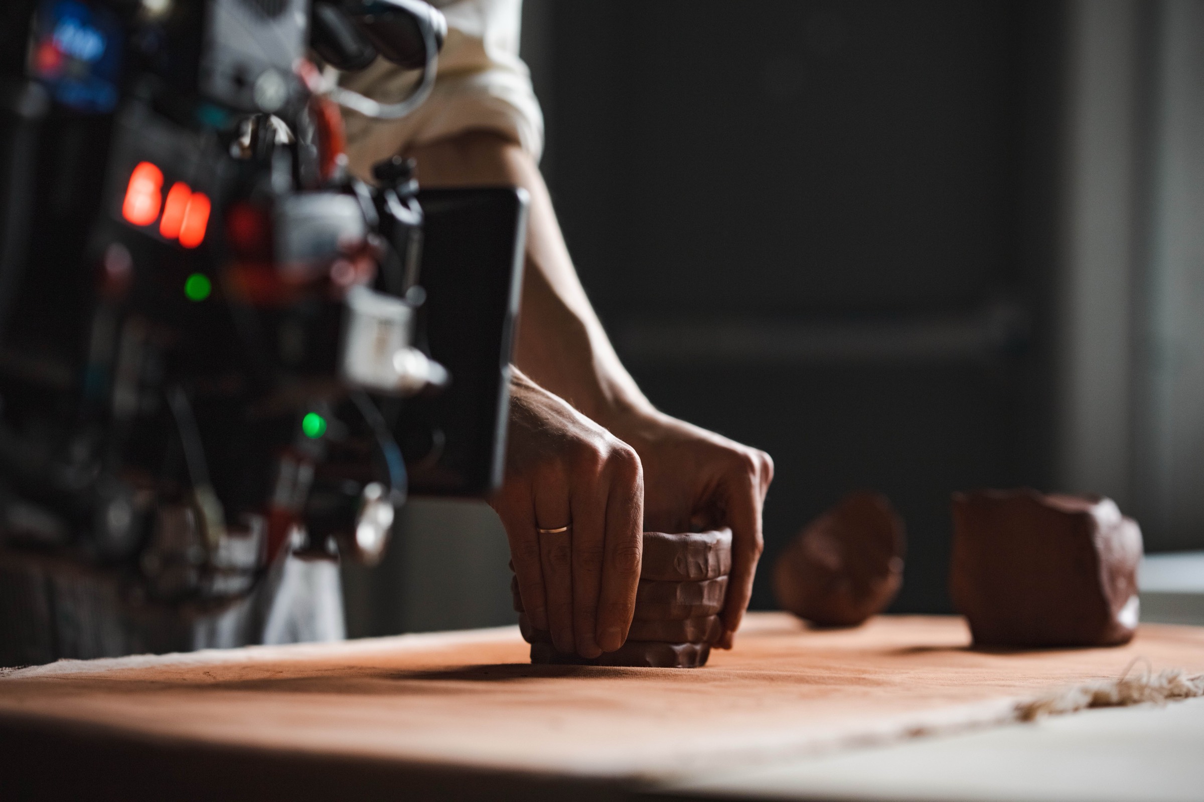 Close-up of hands on clay with cinema camera